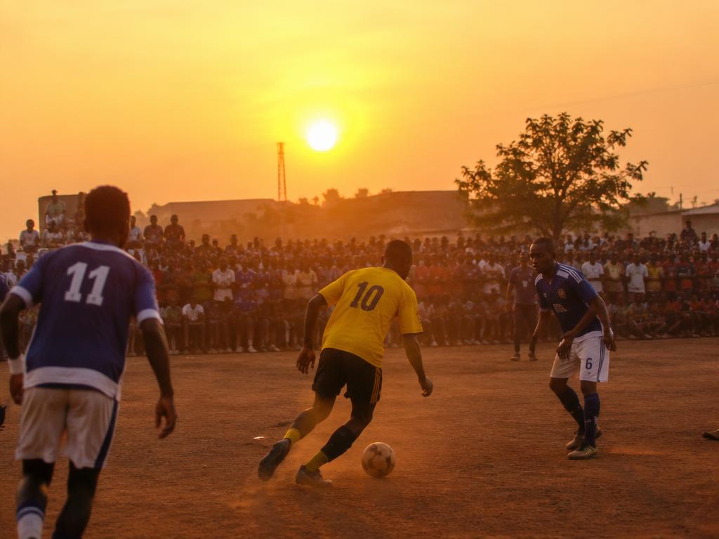 Community football match on a dusty pitch at golden hour